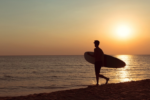 Een surfer bij zonsondergang.