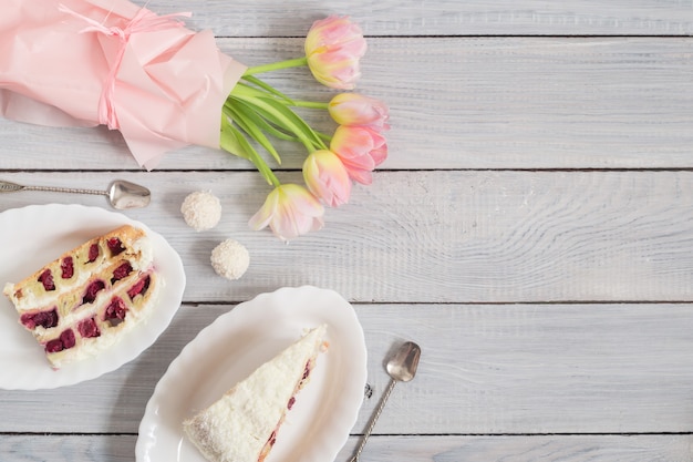 Een taart met kersen en roze tulpen op een witte houten tafel