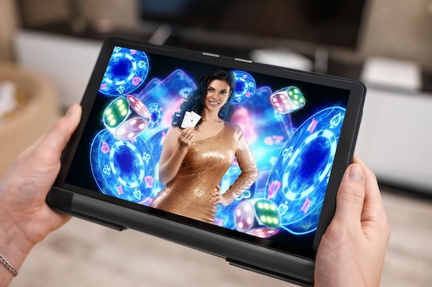 Een tablet in vrouwelijke handen en een neon casino reboot, een mooi meisje met speelkaarten. Online casino, gokken, internetspellen, wedden. sjabloon voor reclame.