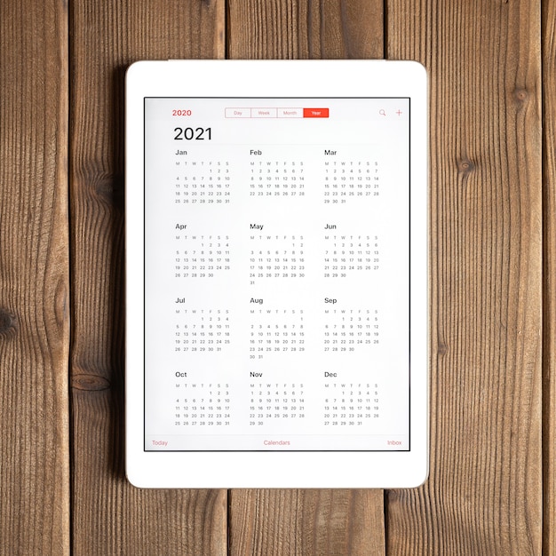 Een tablet met een open kalender voor het jaar 2021 op de achtergrond van een houten planken tafel. vierkant