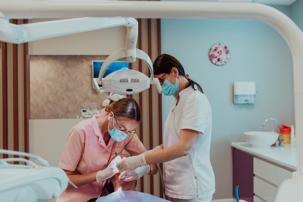 Een tandarts voert met hulp van een collega een operatie uit aan de kaak van een oudere patiënt in een moderne tandheelkundige kliniek. Foto van hoge kwaliteit