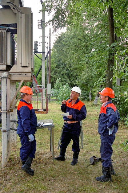 Een team van elektriciens staat bij het onderstation en bespreekt het werkplan voor het onderhoud ervan