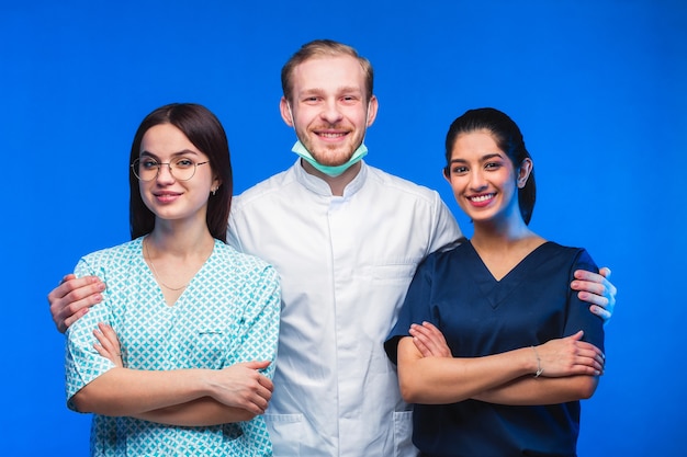 Een team van jonge artsen. Multinationale mensen - arts, verpleegster en chirurg op blauwe achtergrond. Een groep geneeskundestudenten van verschillende nationaliteiten kijkt in de cel.