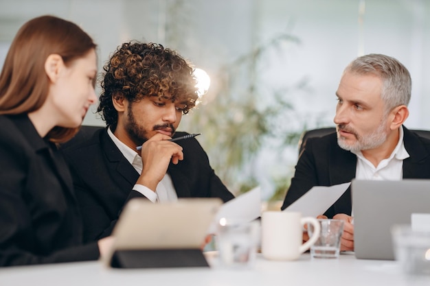 Een team van ondernemers bestudeert documentatie tijdens een vergadering Zakenpartners bestuderen de jaarrekening van het bedrijf van de afgelopen maand