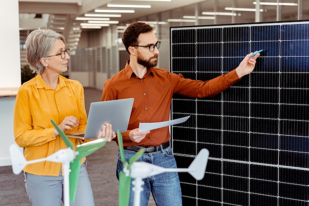 Foto een team van succesvolle ingenieurs die een project plannen met behulp van zonnepanelen en windmolen die op kantoor werken