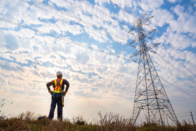 Een technicus bij elektriciteitsmasten met hoog voltage Werken op hoogte-apparatuur Valstopapparaat voor werknemer met haken voor veiligheidsharnas