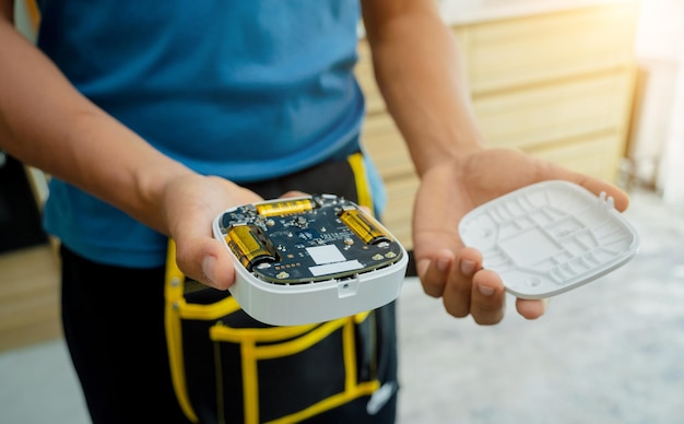 Een technicus installeert een beveiligingsalarm sirene in een modern appartement