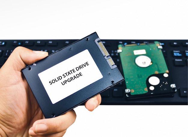 Een technicus toont een Solid State Drive (SSD) harde schijf voor een upgrade van een laptopcomputer