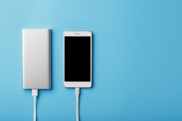 Een telefoon opladen met powerbank op blauwe achtergrond. Houd de batterij altijd opgeladen op uw apparaat.