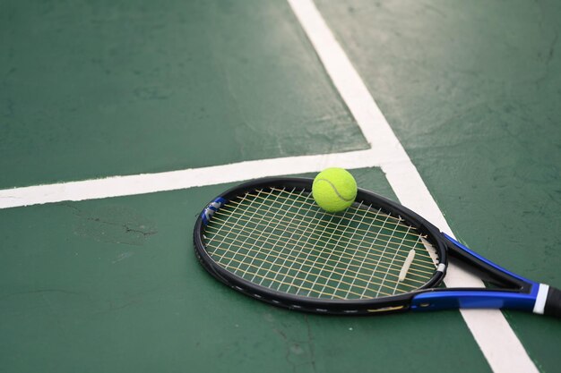 Een tennisracket en een bal op de groene vloer van de baan met zonlicht Buitensporten en een gezond levensstijlconcept