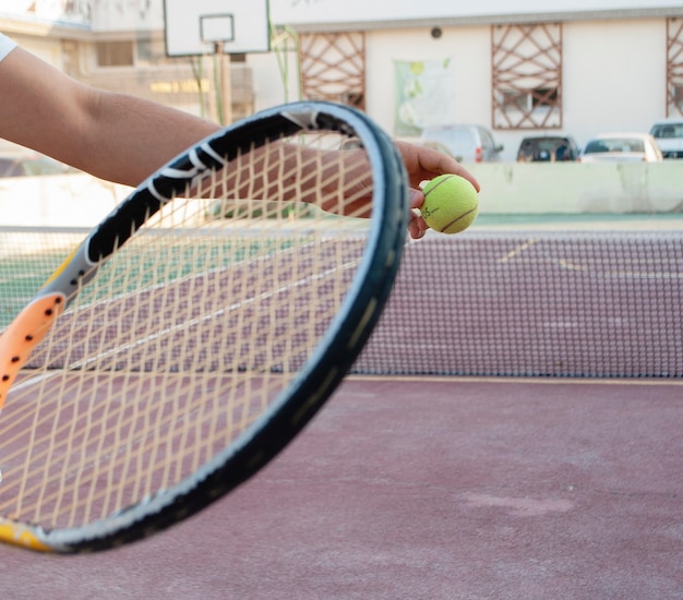 Een tennisracket en een tennisbal op de achtergrond van een tennisbaan.