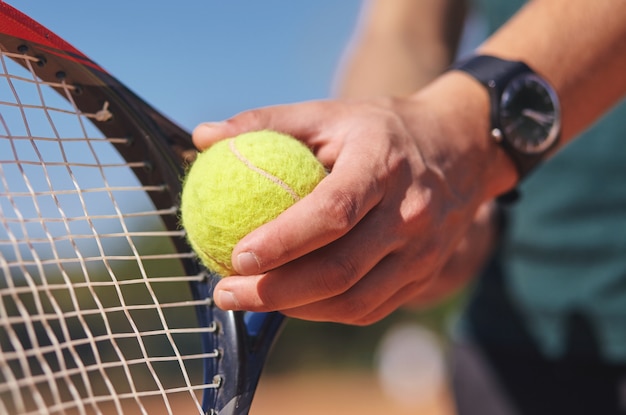 Een tennisser met racket en bal in handen