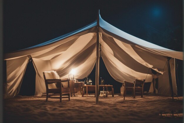 een tent met een tafel en stoelen op het strand 's nachts.