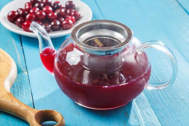 Foto een theepot met hibiscusthee ernaast op een blauwe tafel op een houten kers in een bord