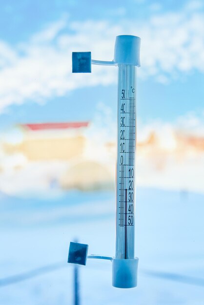 Een thermometer in de buitenlucht wordt met lijmband aan het vensterglas buiten op een schaal van graden bevestigd