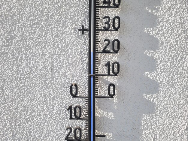 Foto een thermometer op een witte muur in het zonlicht