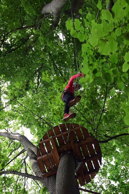 Een tiener beklimt een hangende ladder in een touwpretpark