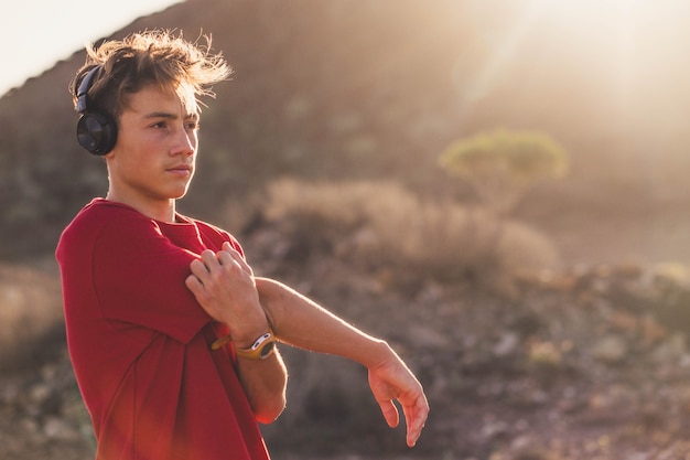 Een tiener die alleen rent of jogt in de heuvels - man die zich uitstrekt, luistert naar muziek met een koptelefoon na een trainingssessie