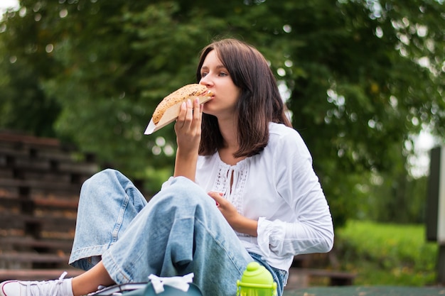 Een tiener eet een broodje in het park