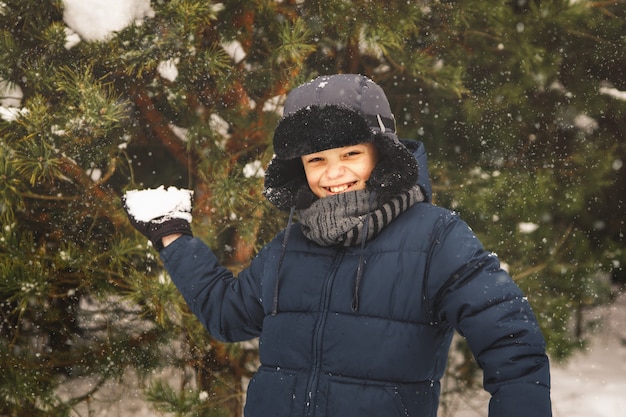 Een tiener gooit een sneeuwbal. Speelt in de winter in het park