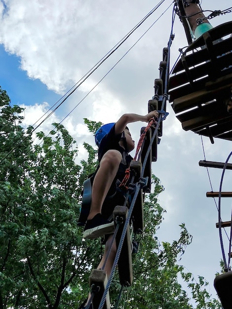Een tiener klimt op een touwladder in een touw pretpark Uitzicht van beneden