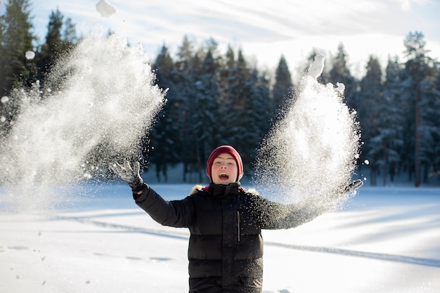 Foto een tiener speelt met sneeuw in het bos op een zonnige winterdag. fijne winterspelen en een gezonde levensstijl.