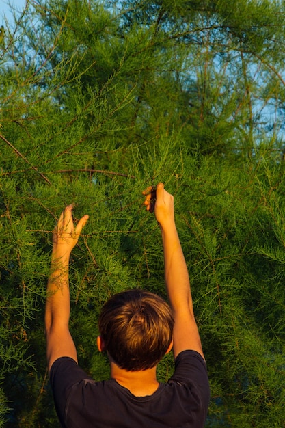 Een tiener zorgt voor een jonge boom door te tuinieren om het wereldconcept natuur, milieu en ecologie te redden Onderwijs en schoolkinderen planten jonge fruitbomen buitenshuis