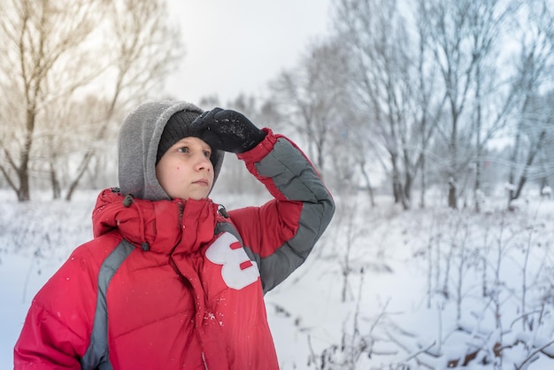 Een tienerjongen speelt in de winter buiten in de sneeuwbanken