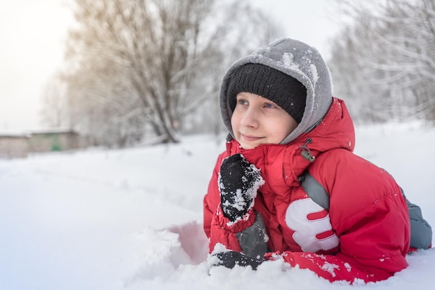 Een tienerjongen speelt in de winter buiten in de sneeuwbanken