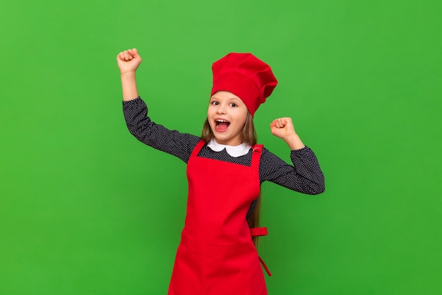 Een tienermeisje heeft een chef-koksuniform aangetrokken en is erg blij dat ze een kind zal koken in de vorm van een kok op een afgelegen groene achtergrond