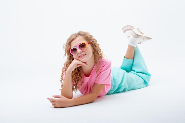 Een tienermeisje in hartvormige zonnebril ligt op een witte achtergrond