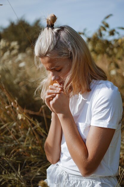 Een tienermeisje sloot haar ogen terwijl ze in een veld bad. Handen gevouwen in gebed, geloof, spiritualiteit en religie concept.