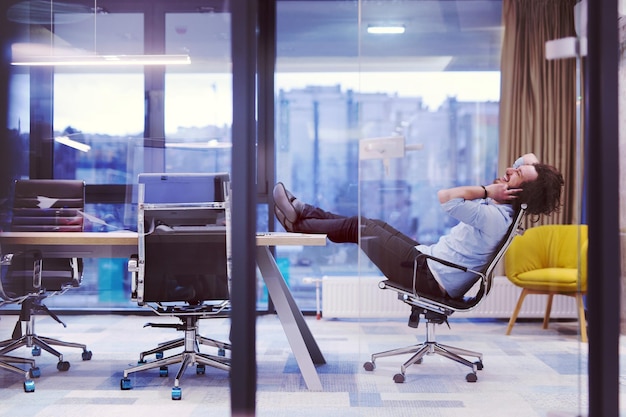 Een tijd om te ontspannen. Jong moe casual zakenman ontspannen aan het Bureau in zijn kantoor