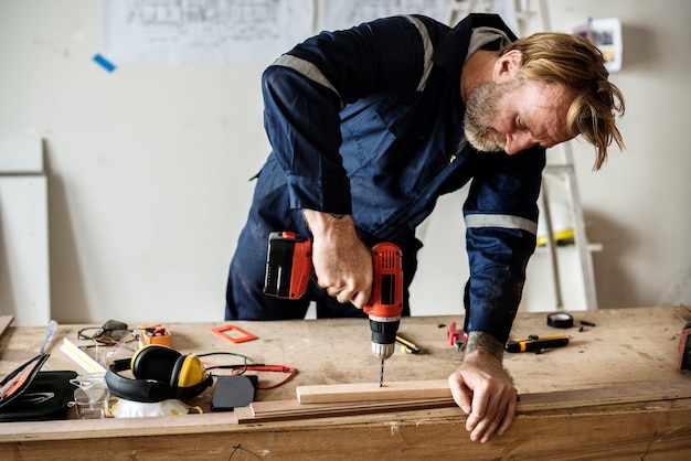 Een timmerman die een boor op een hout gebruikt