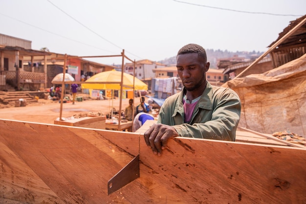 Een timmerman snijdt een plank met een handzaag in zijn werkplaats in Afrika