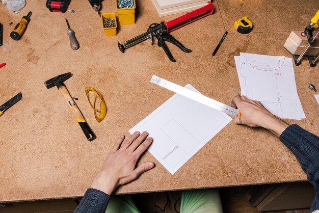 Een timmerman werkt in een meubelwerkplaats met diverse gereedschappen en een bord