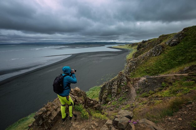 Een toerist fotografeert een zwart strand op het Vatnsnes-schiereiland Hvitserkur IJsland