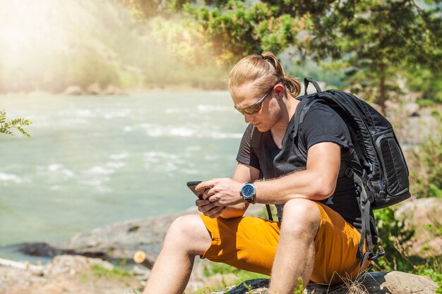 Een toerist met een telefoon en een rugzak op de bergen in de oppervlakte