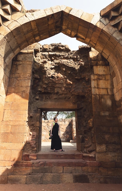 Een toerist staat onder de boog van het Qutub Minar-complex India