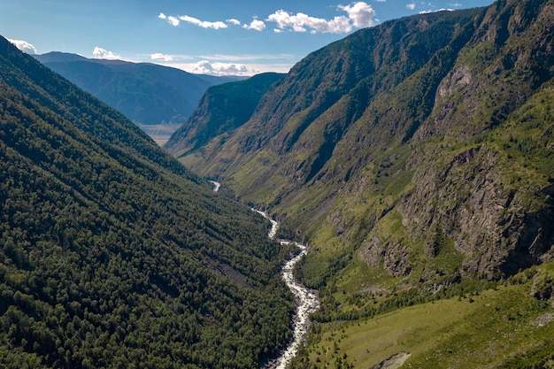 Een toeristenfotografie vanuit een helikopter met uitzicht op een stromende smalle rivier tussen twee rotsachtige hoge heuvels.