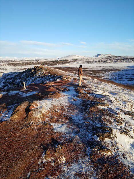 Een toeristenkerel loopt dichtbij Kerid-meer in de winter in IJsland. Ongelofelijk winterlandschap van IJsland