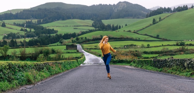 Een toeristenvrouw die alleen midden op de weg loopt om plezier te hebben in de buurt van een prachtig landschap