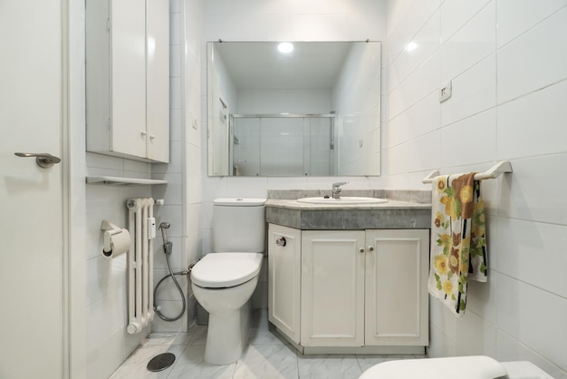 Een toilet met een wastafel verzonken in een grijs marmeren werkblad