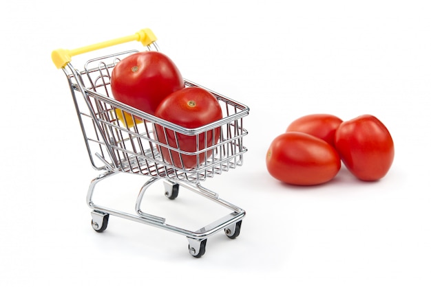 Een tomaat in winkelwagen geïsoleerd op een witte achtergrond. Rijpe smakelijke rode tomaten in winkelwagen. Tomaat handelsconcept. Online winkelen concept. Kar en tomaat op een witte achtergrond.