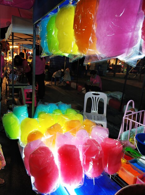 Een toonbank die gekleurde suikerspin verkoopt op een nachtelijke straatvoedselmarkt in Azië.