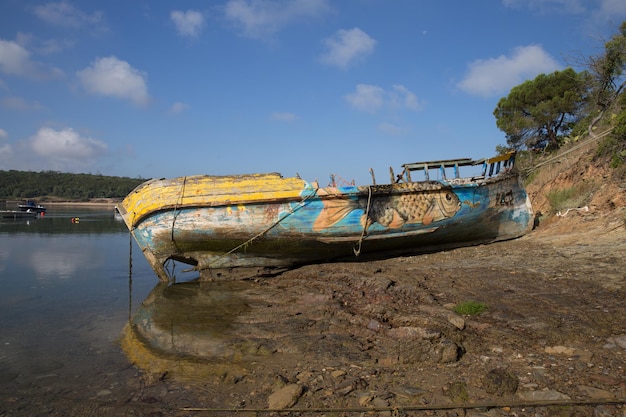 Een totaal vernielde boot ligt naast de rivier