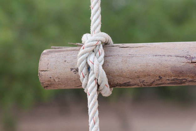 Foto een touw is gebonden in een knoop rond een hek post, touw vastgebonden knoop houten paal