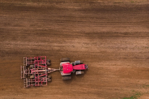 Een tractor met een schijveneg ploegt een veld om om te zaaien Luchtfotografie