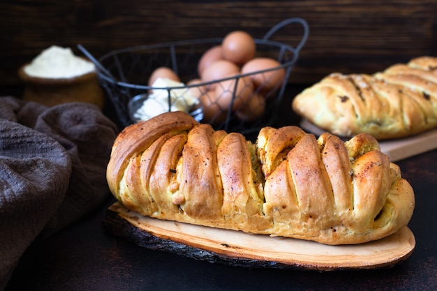 Een traditionele zoute taart uit de Russische keuken genaamd kulebyaka. Ingrediënten voor het deeg boter, bloem, eieren. Taart met vlees en kool. Donkere rustieke achtergrond. Detailopname