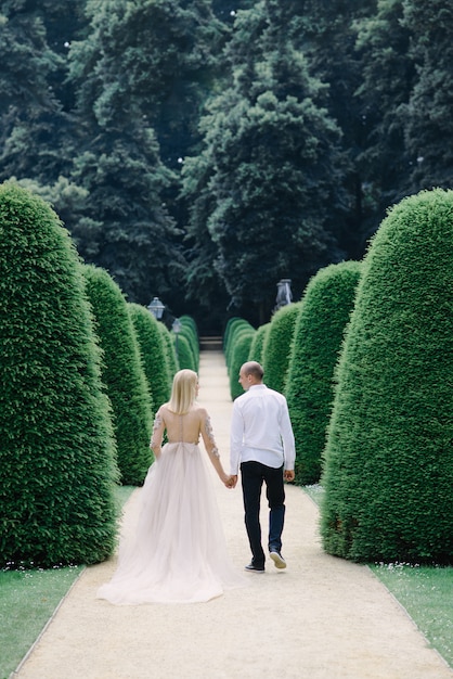 Een trendy jong stel wandelt in de zomer door de stad, de jonge vrouw draagt een luxe jurk